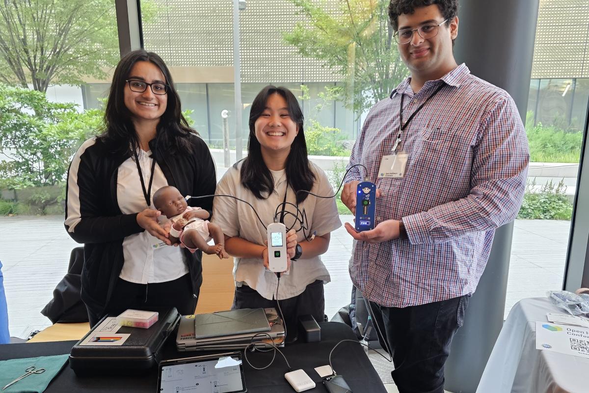 Three Olin College students hold their prototype hearing screening device for children.