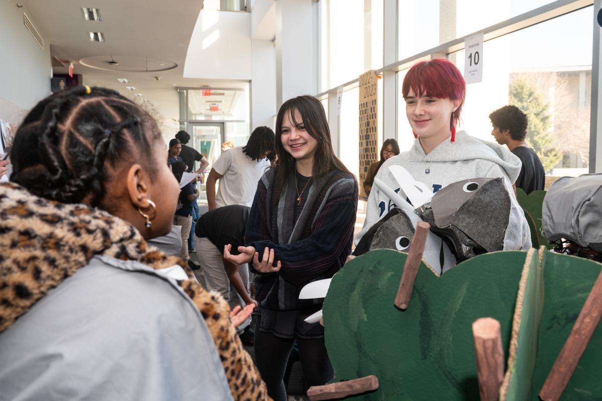 Two Olin College of Engineering students talk with a local 4th grade student during Design Nature's Play Experience Demo.