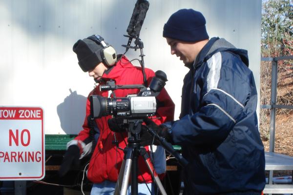 Kevin Tostado ’06 stands with a camera. 