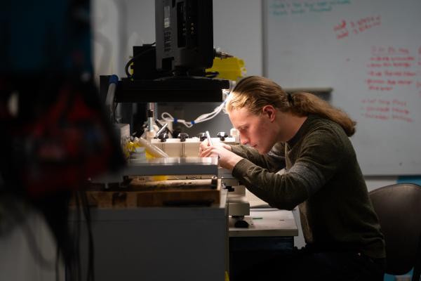 An Olin AERO project team student works with tools at a workbench.