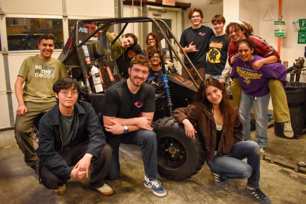 A group of Olin Baja members pose around the vehicle in the LPB.