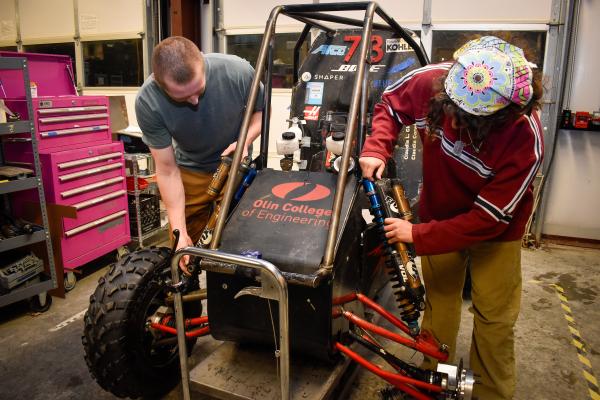 Two Olin Baja project team students work together on the car's suspension.