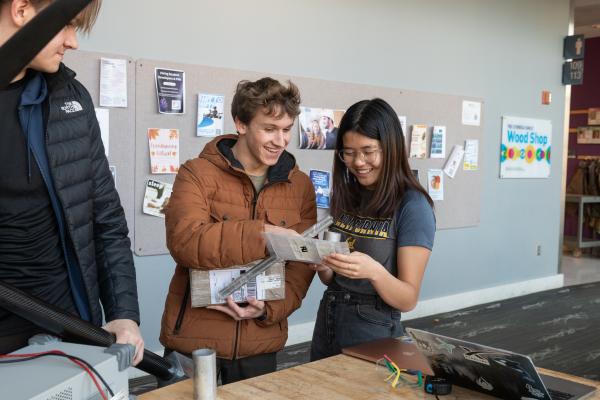 Three Olin OCTAL project team members smile while reading a parts manual.