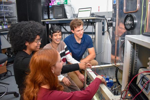 Four Olin OPEL project team members smile and adjust their equipment.