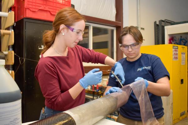 Two Olin Rocketry project team members work together at a workbench.