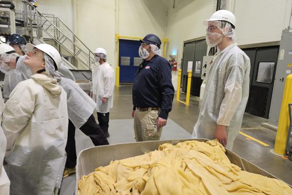 Students and staff stand near a bucket of pasta. 