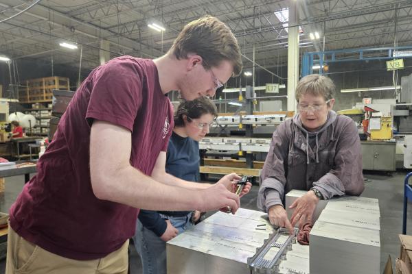 Two students stand with a team member from Darco Manufacturing. 