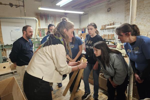 An employee from O&G Studio shows students two pieces of wood.
