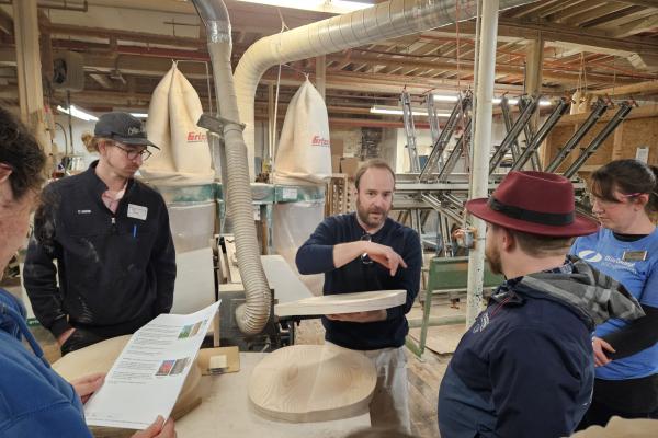 Coby Unger and students listen to a member of O&G Studio speak about their manufacturing process. 