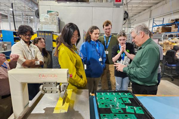 Students gather around a Z-AXIS/Bear Power Supplies Facility Tour presenting information. 