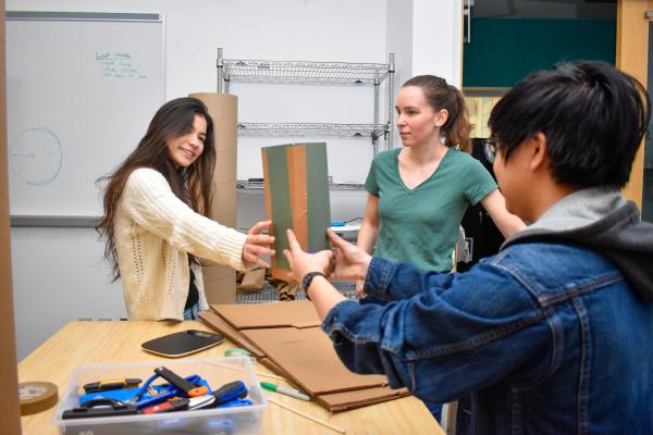 Two students exchanging parts of their MechProto Build Challenge.
