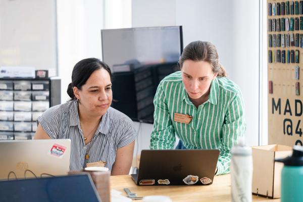 Georgia Van de Zande looks at a computer screen with one of the Makerspace Institute participants.
